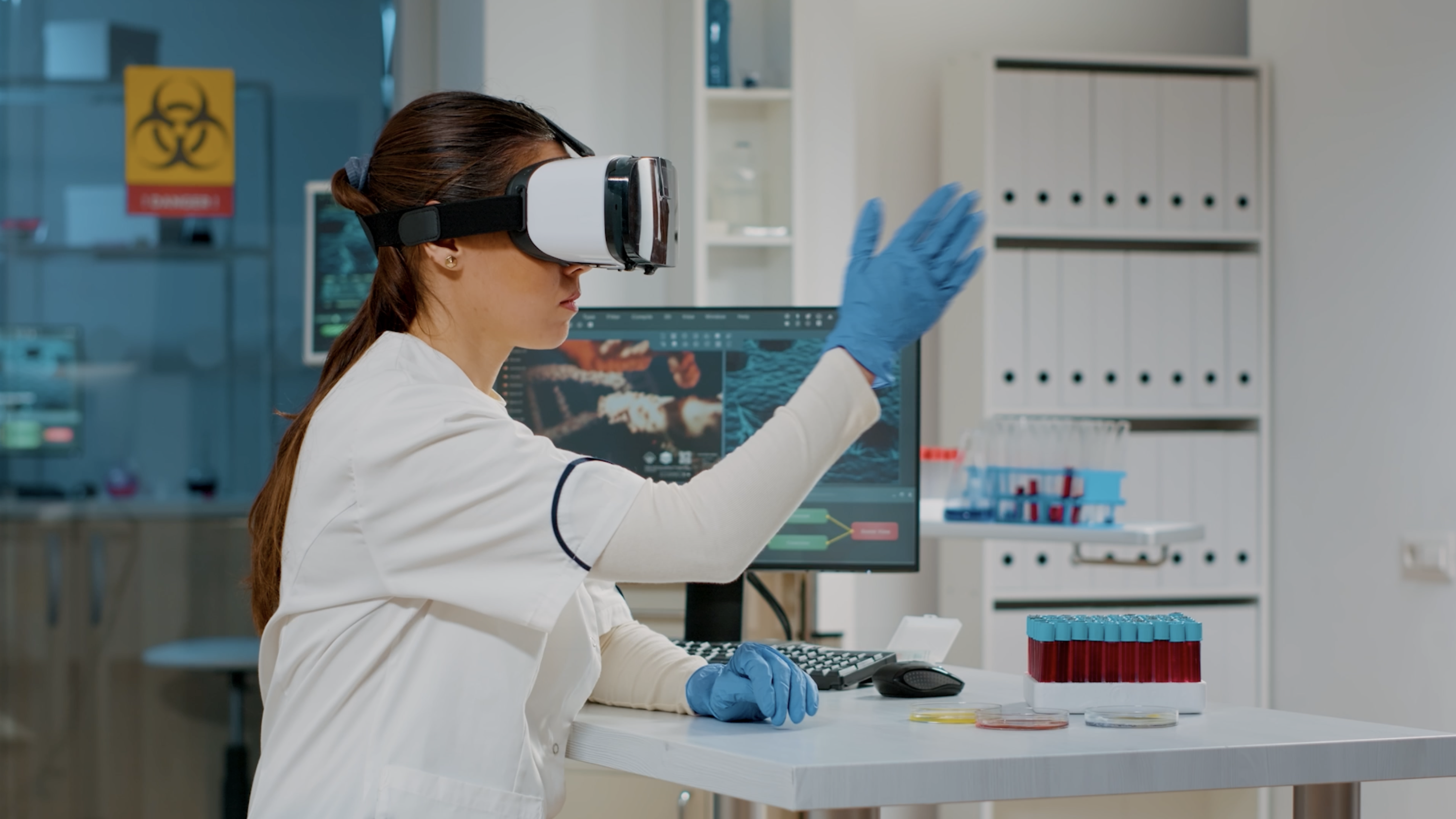 Female medical professional wearing a virtual reality headset and gloves, interacting with a digital interface in a laboratory setting, surrounded by test tubes and laboratory equipment, illustrating the application of XR technology in healthcare education.